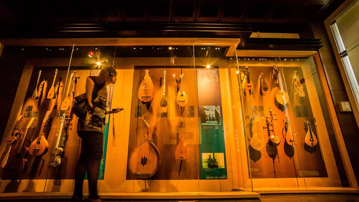 Um visitante usando fones de ouvido observa uma vitrine de vidro repleta de instrumentos de corda no Museu dos Instrumentos Musicais (MIM) em Bruxelas.
