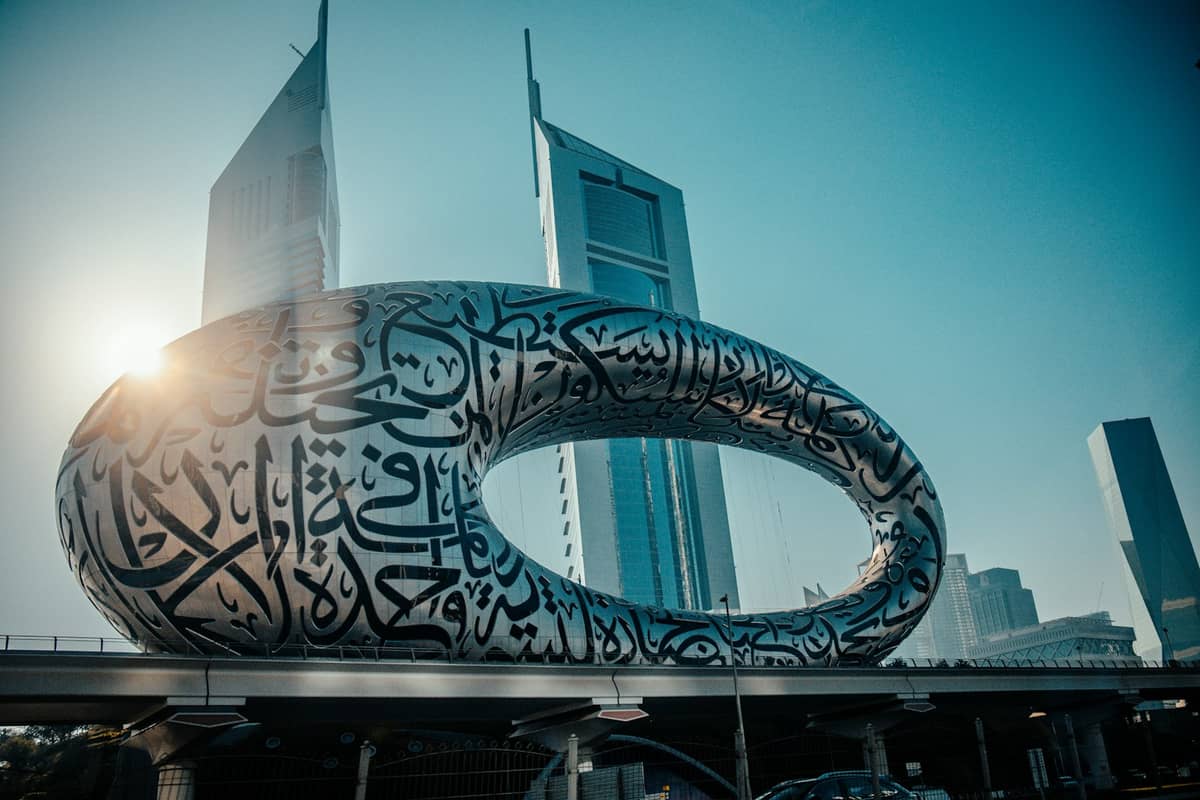 Außenansicht des Museum of the Future in Dubai mit seiner markanten Torusform, bedeckt mit arabischer Kalligrafie und umgeben von modernen Wolkenkratzern.