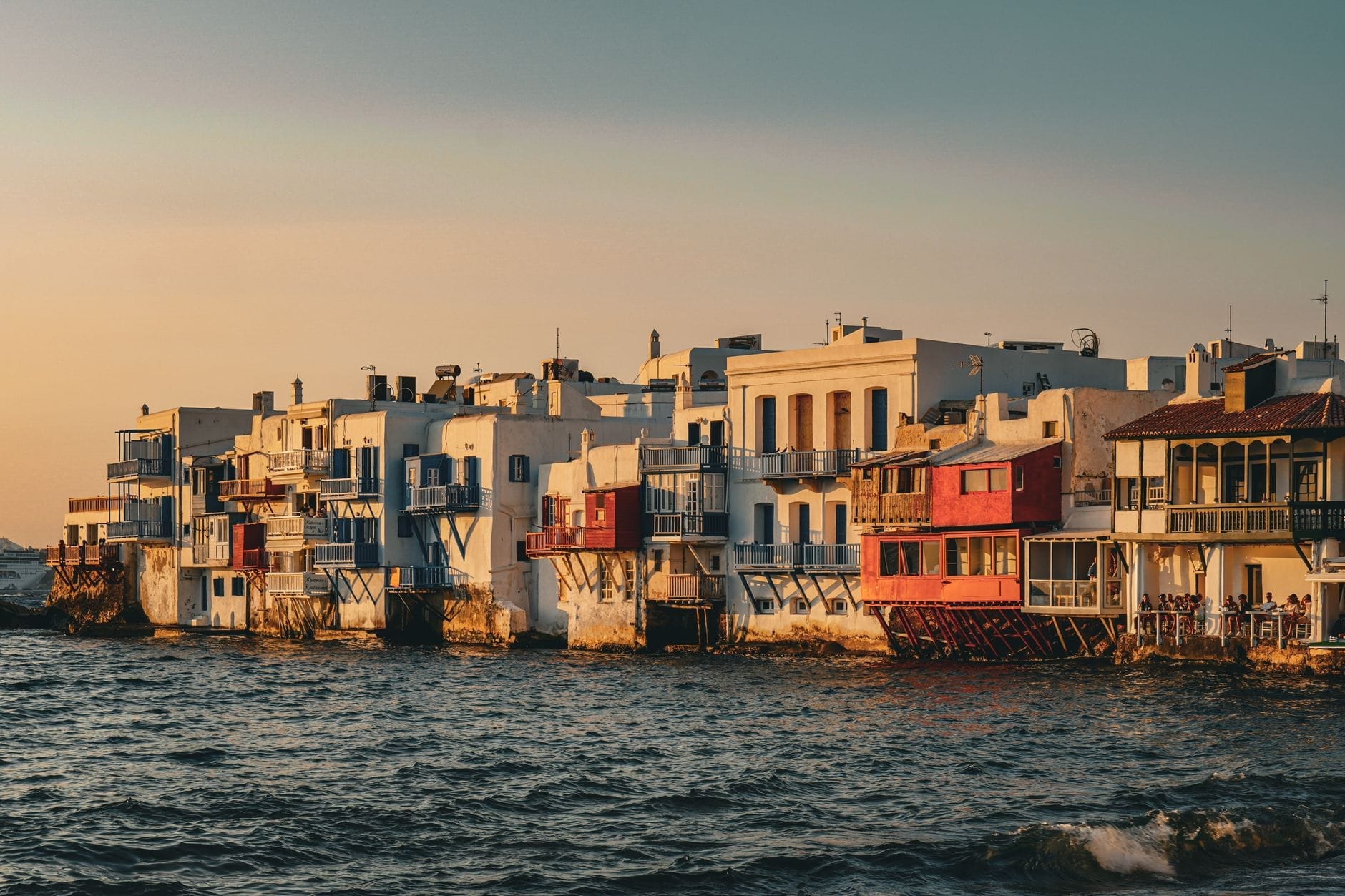 La Pequeña Venecia de Mykonos al atardecer, con sus icónicos bares junto al mar y edificios encalados a orillas del mar.