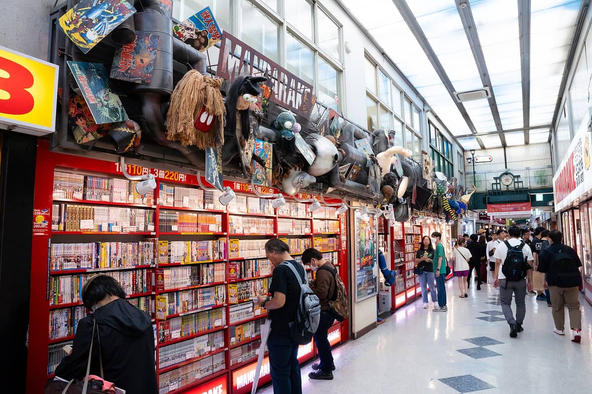 Interior hallway of Nakano Broadway with manga shelves, collectors browsing, and distinctive Mandarake store decorations above the storefronts.