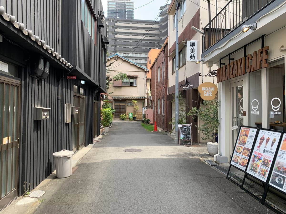 A quiet pedestrian alley in Nakazakicho lined with early-Showa-era wooden townhouses and a modern cafe, illustrating the neighborhood’s blend of history and indie culture.