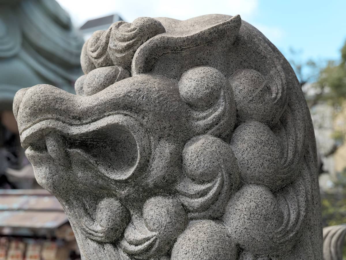 Close-up of the stone lion head from Namba Yasaka Shrine, with part of the giant lion stage visible in the background.