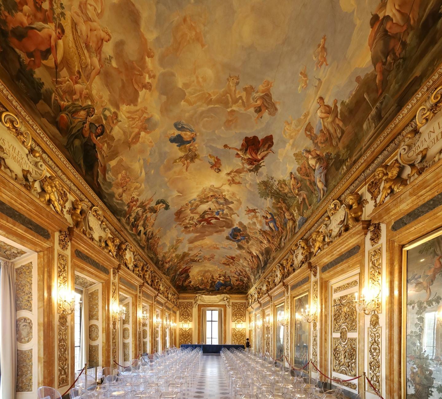 Salle somptueusement décorée dans un palais italien avec un plafond peint époustouflant, des accents dorés, des lustres et d'élégants miroirs.