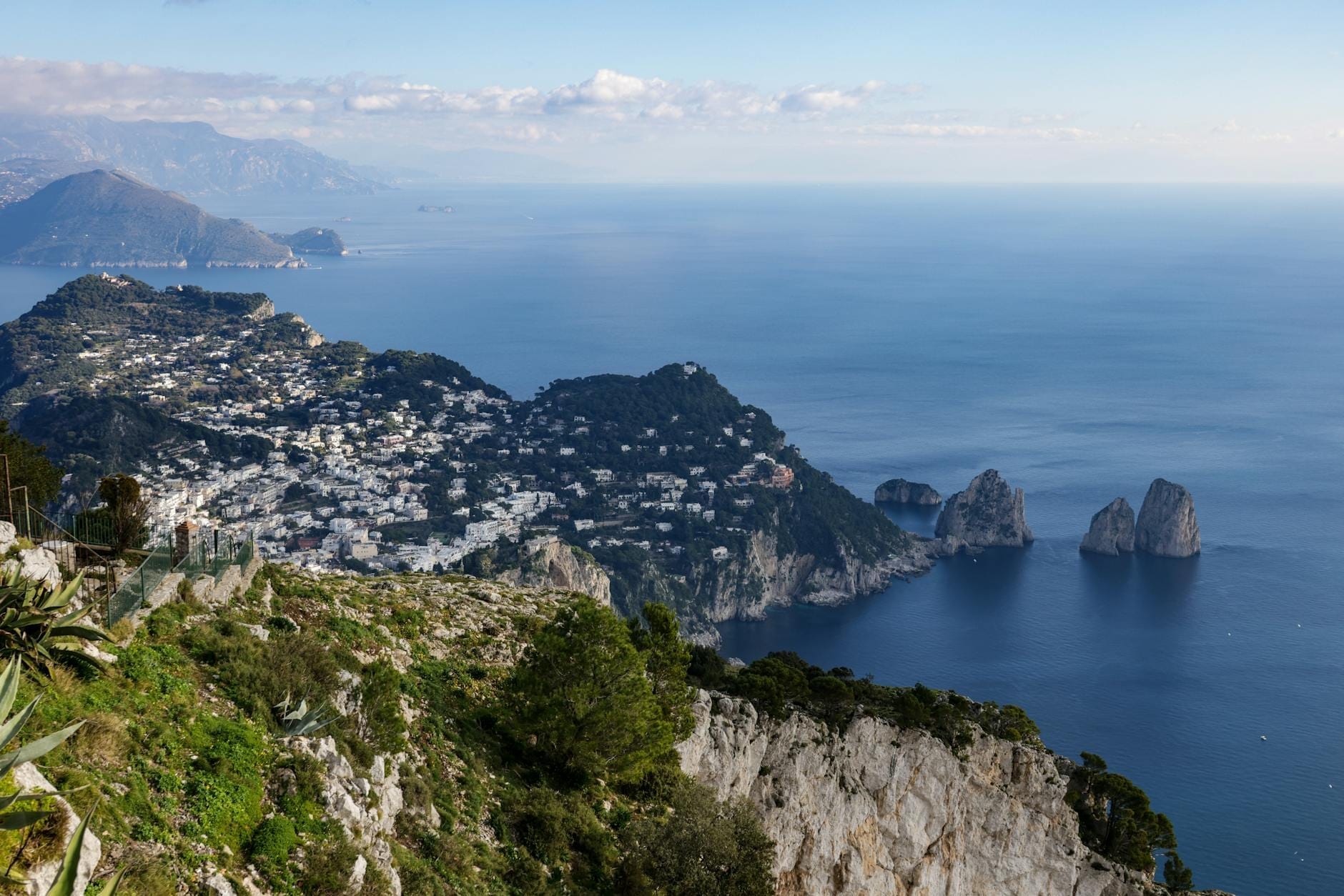 Vue panoramique de l'île de Capri avec des bâtiments blanchis à la chaux, des falaises spectaculaires, les Faraglioni et la mer s'étendant vers le littoral de Naples.