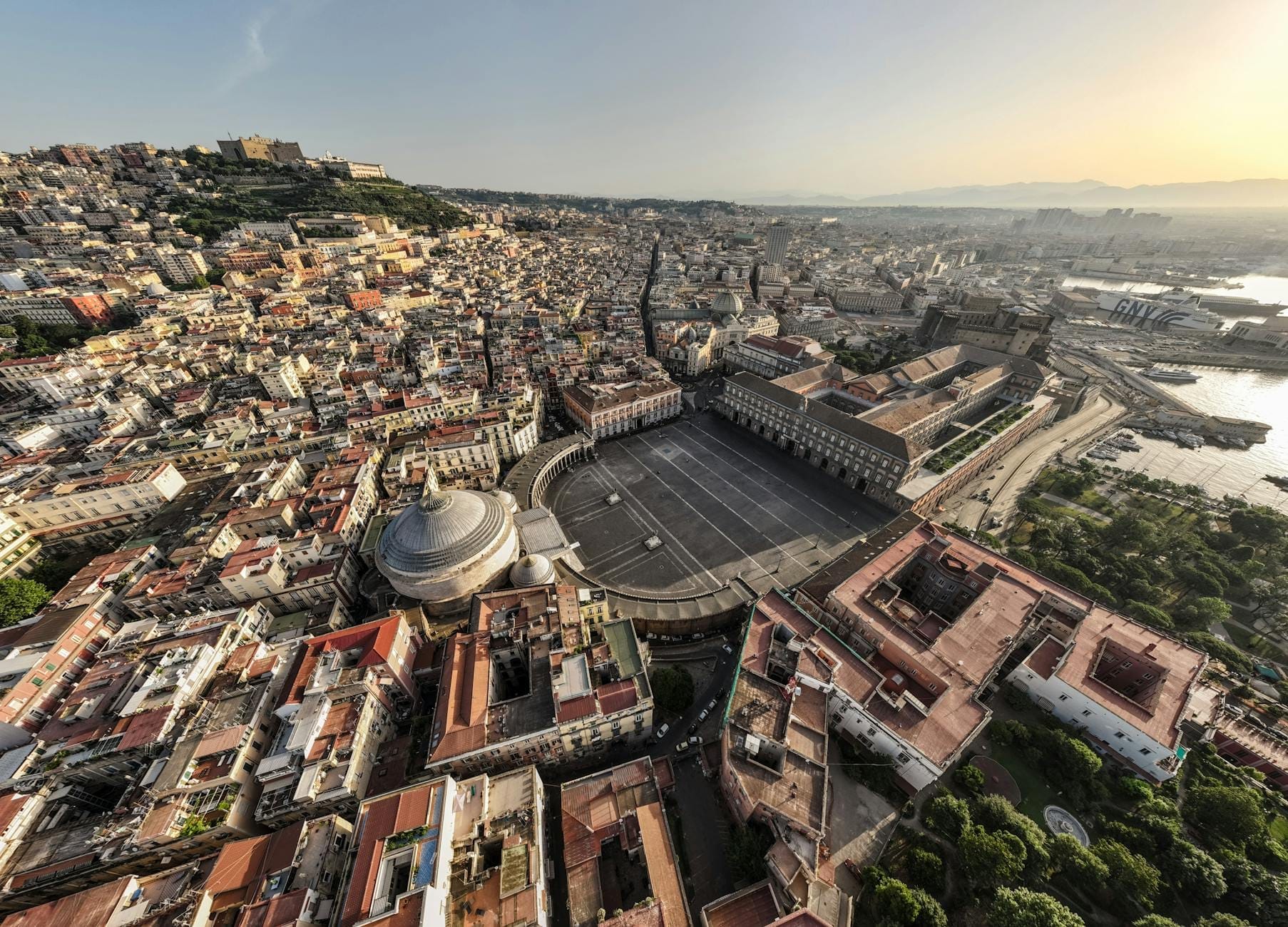 Vue aérienne panoramique de Naples avec la Piazza del Plebiscito, le Palais Royal, le Castel dell'Ovo et la baie au coucher du soleil.