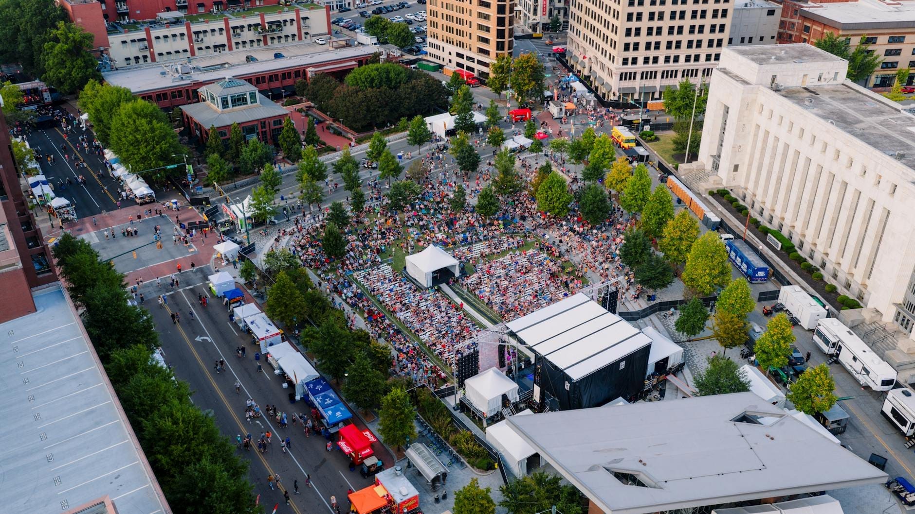 Vista aérea de un evento al aire libre en el centro de Nashville con multitudes, food trucks y edificios cercanos en un día soleado.