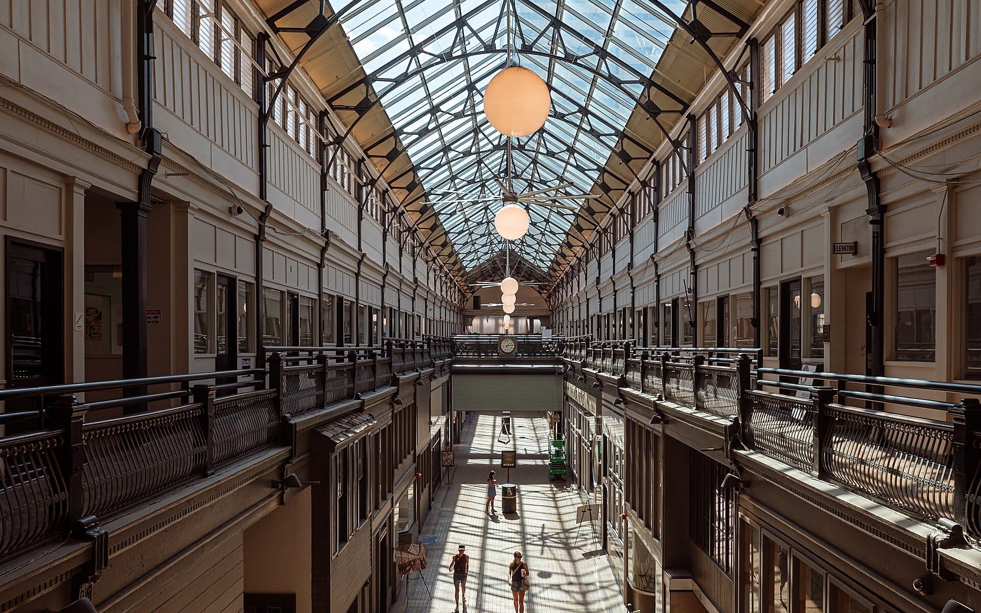 Vista interior del Nashville Arcade con techo de cristal, barandillas vintage y personas caminando abajo a la luz natural del día.