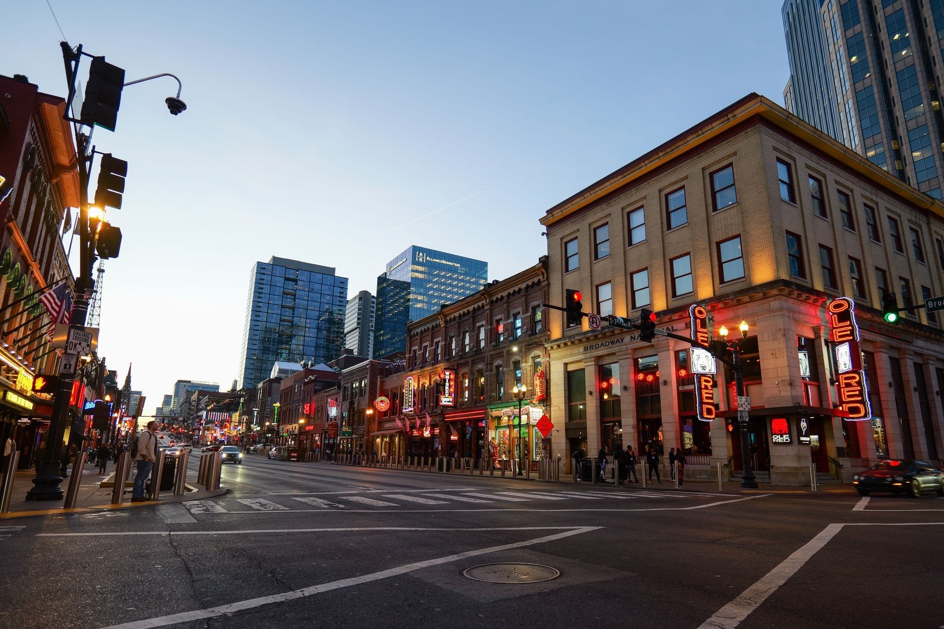 Vista del centro de Nashville al atardecer con animados honky-tonks, letreros de neón y luces brillantes que invitan a disfrutar de música en vivo.