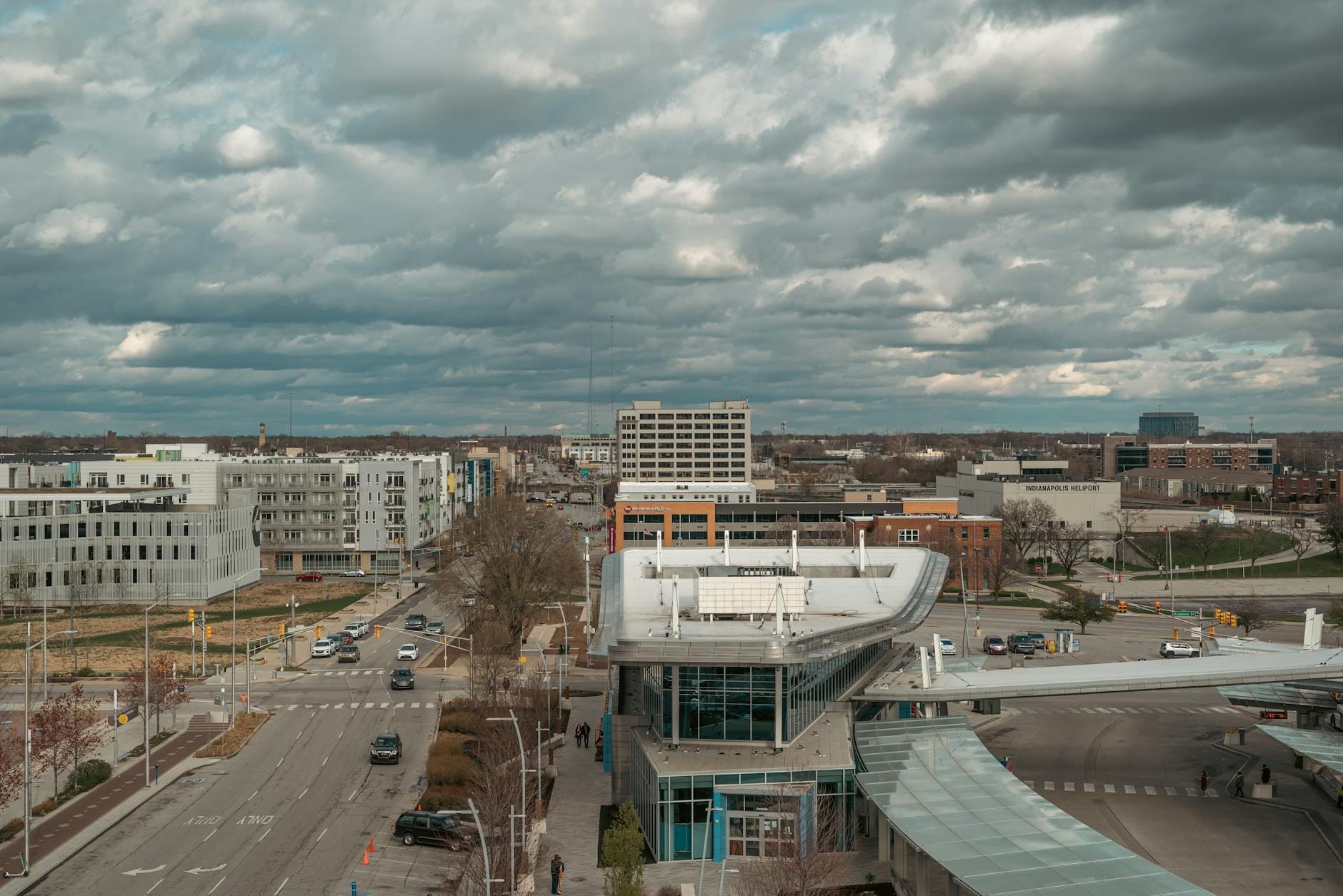 Vista aérea de una calle de Nashville y un centro de transporte con edificios modernos y cielo nublado, evocando un punto de llegada o tránsito a la ciudad.
