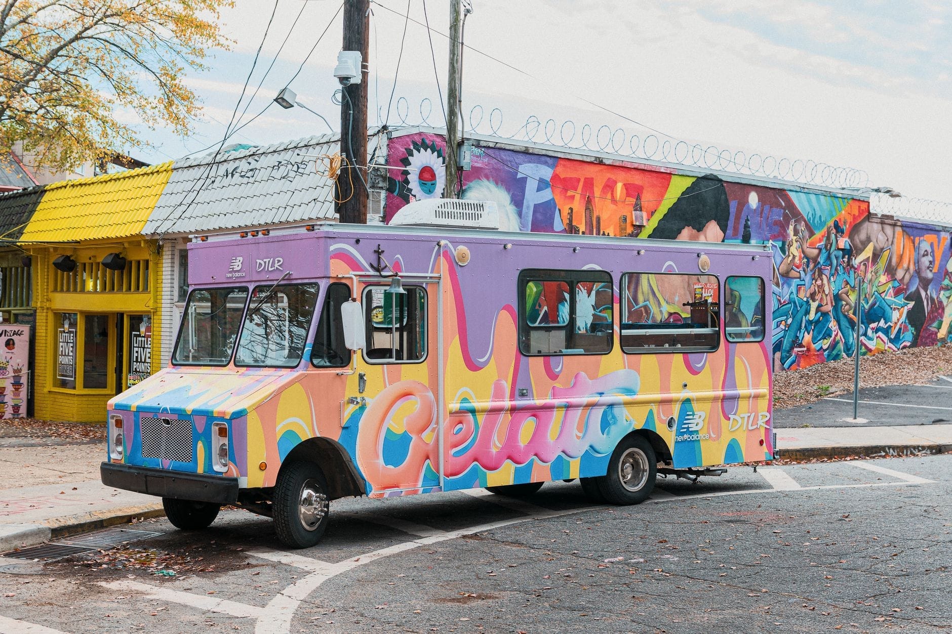 Colorido camión de gelato estacionado en la calle frente a edificios con murales, fachada amarilla y vibrante comercio indie típico de East Nashville.
