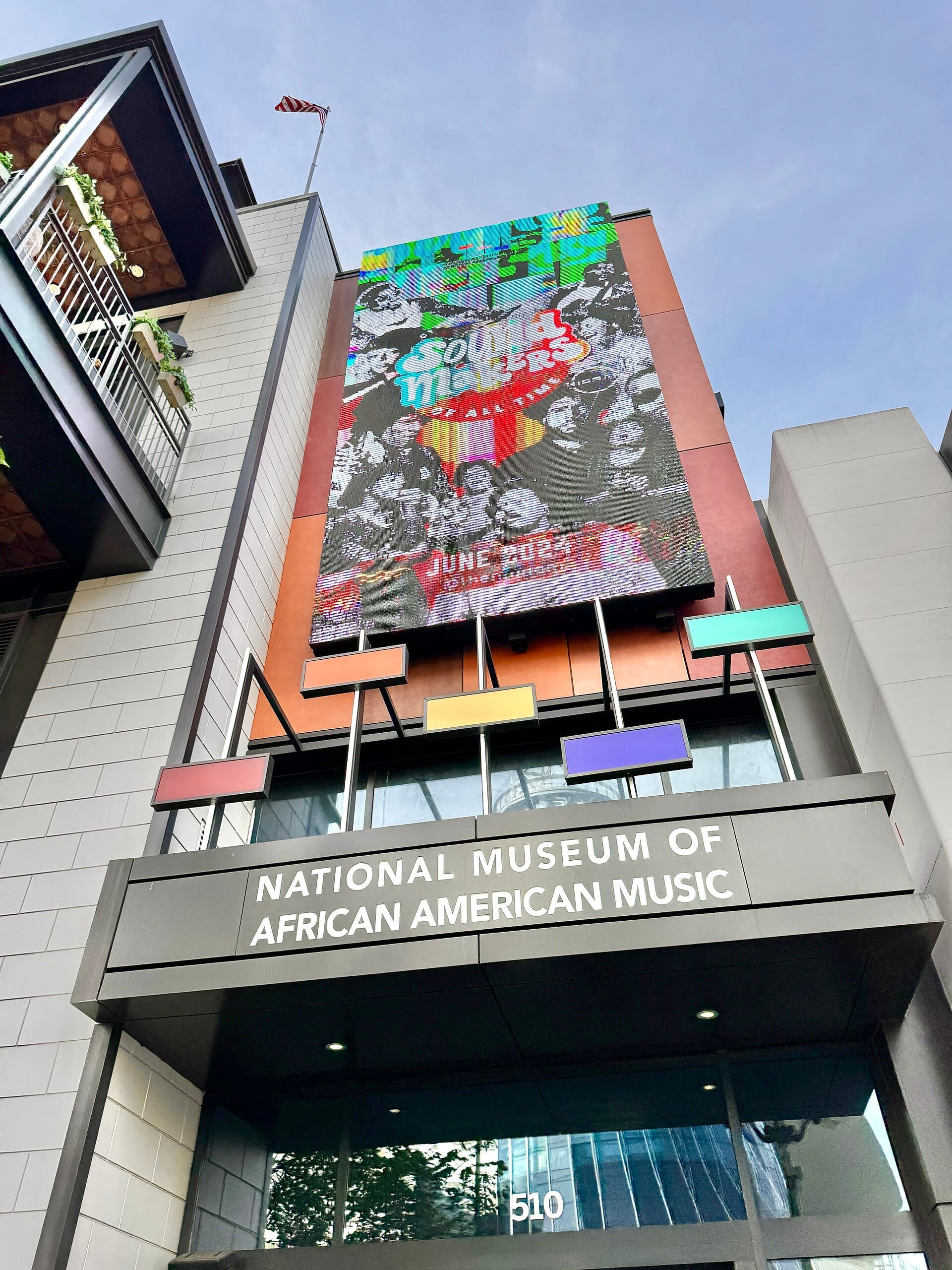 Entrada del National Museum of African American Music en Nashville con marquesina colorida y detalles arquitectónicos modernos bajo un cielo azul.