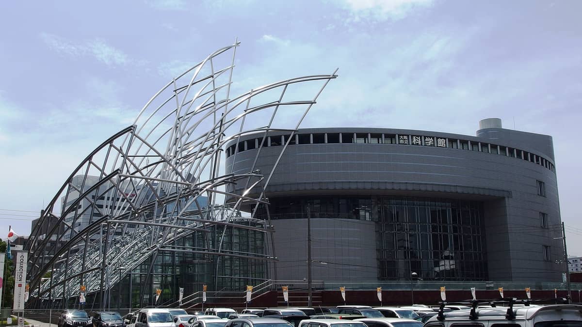 Exterior view of the National Museum of Art, Osaka, featuring its distinctive sculptural steel entrance structure and modern architecture under a blue sky.