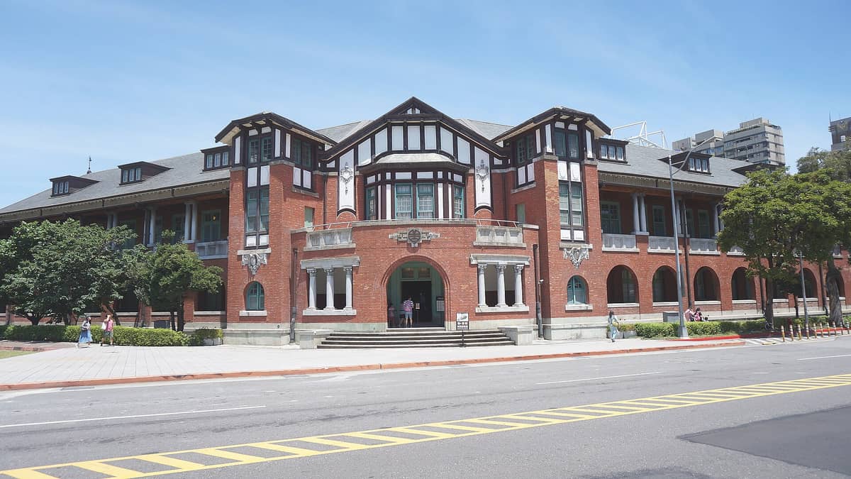 Das historische Backsteingebäude des Nationalmuseums Taiwan – Eisenbahnpark mit Tudor-Elementen und Bogendurchgang vor blauem Himmel in Taipeh.