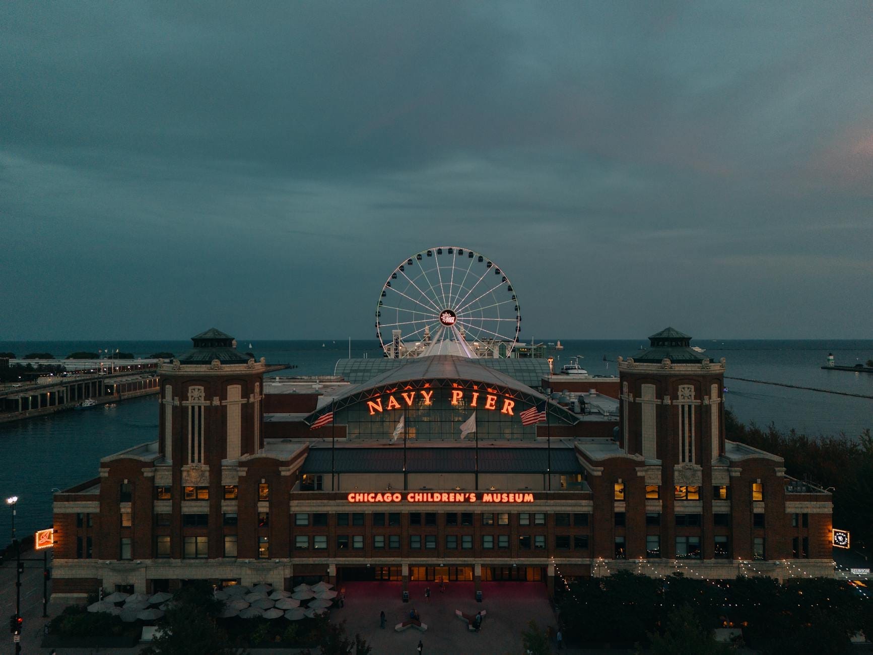 Vista aerea del Navy Pier di Chicago al crepuscolo, con la ruota panoramica illuminata e il lago Michigan sullo sfondo.