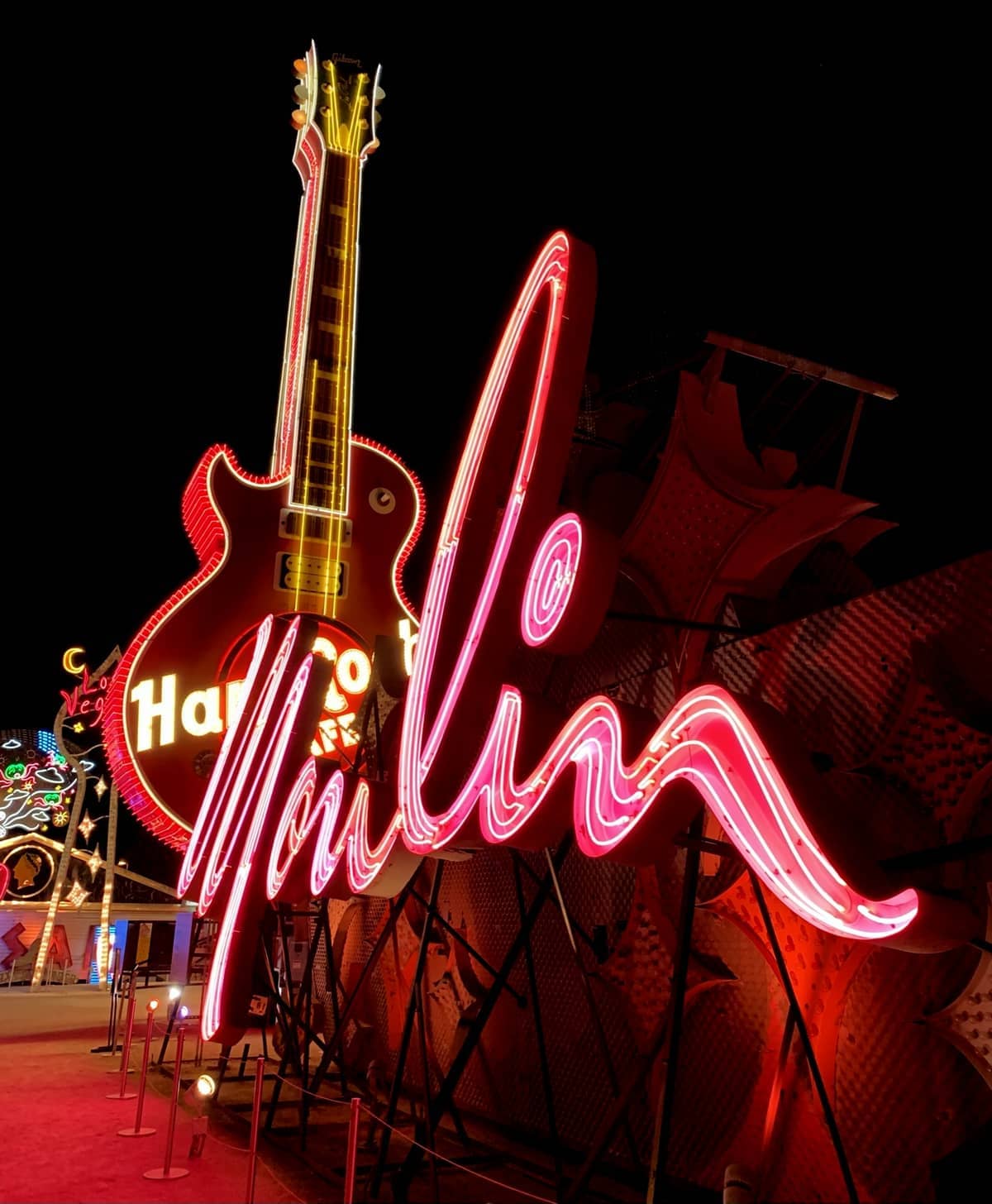Große Neonreklamen, darunter ein rosafarbenes 'Y' in Schreibschrift und eine leuchtende Gitarre, sind nachts im The Neon Museum in Las Vegas erleuchtet.