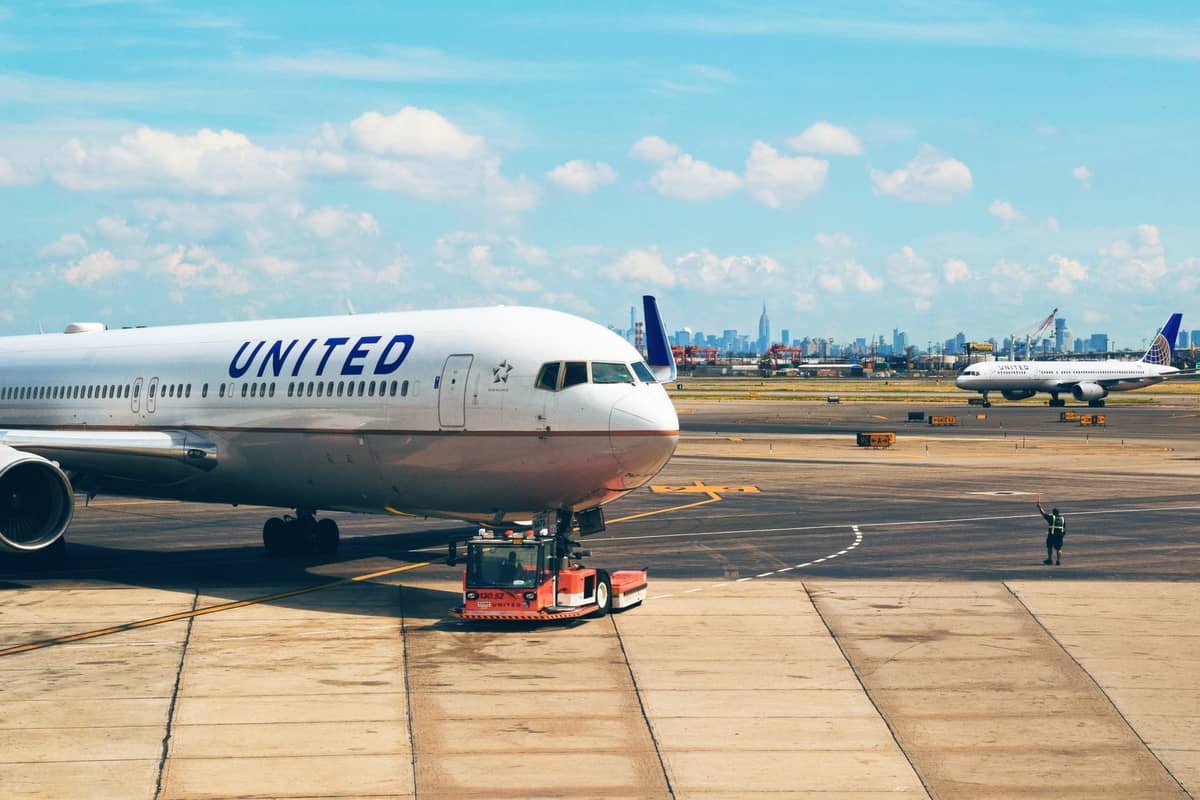 วิวเครื่องบินของ United Airlines บนลานจอดของสนามบินโดยมีเส้นขอบฟ้าของ New York City ปรากฏให้เห็นในพื้นหลังที่ไกลออกไป