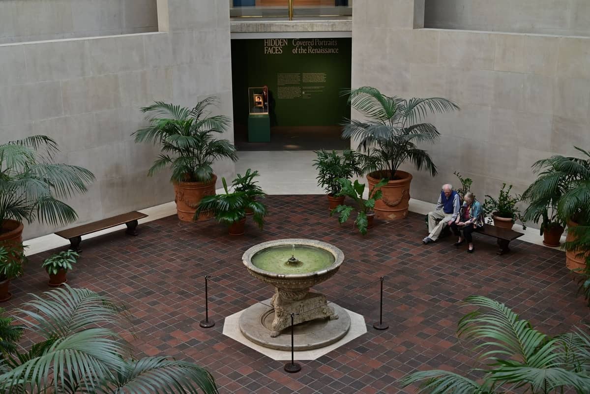 Ruhiger Museumshof mit einem Steinbrunnen, grünen Pflanzen, Bänken und einer stillen, intimen Atmosphäre in New York City.