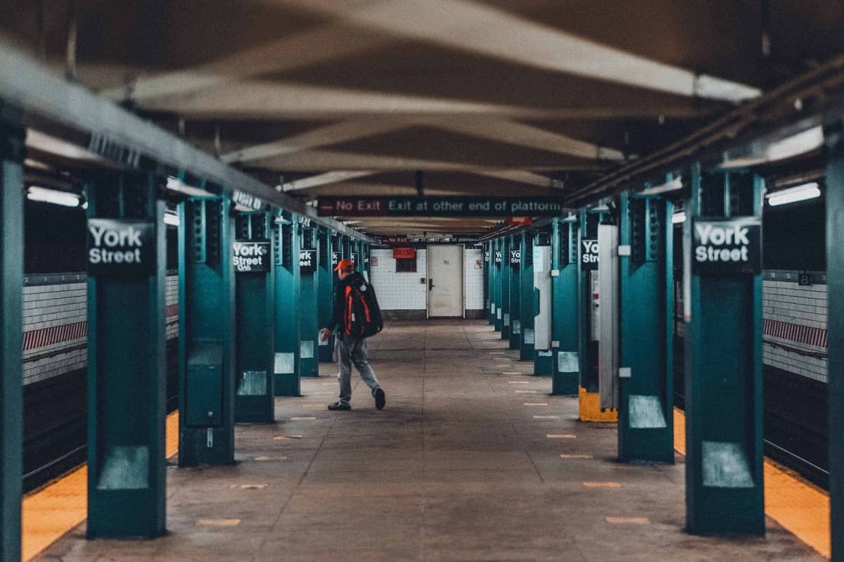 Person, die auf dem Bahnsteig der U-Bahn-Station York Street in Brooklyn läuft, mit sichtbaren Säulen und Schildern.