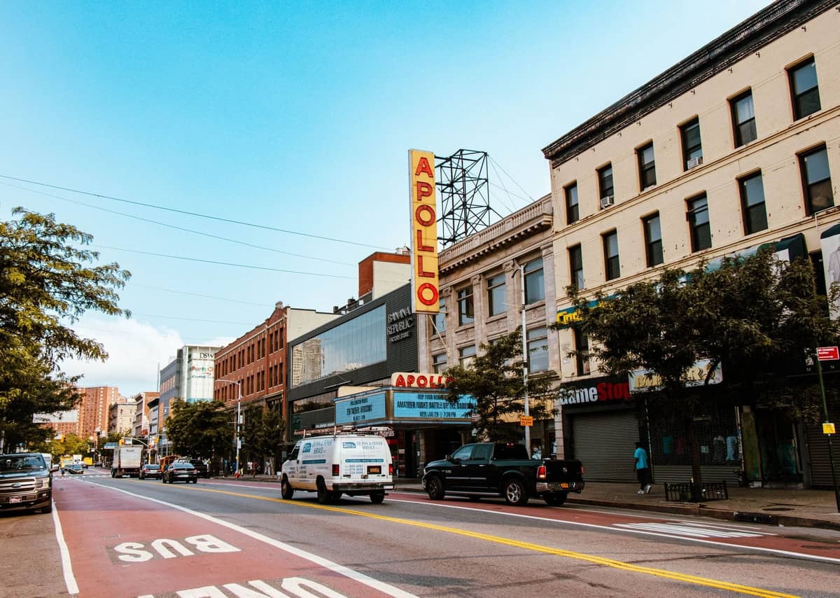 Straßenansicht des Apollo Theater in Harlem, New York City, mit seinem ikonischen roten Neonschild über dem Eingang.