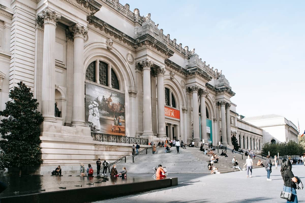 Weitwinkelansicht des Haupteingangs des Metropolitan Museum of Art in New York City mit Besuchern auf den Stufen.