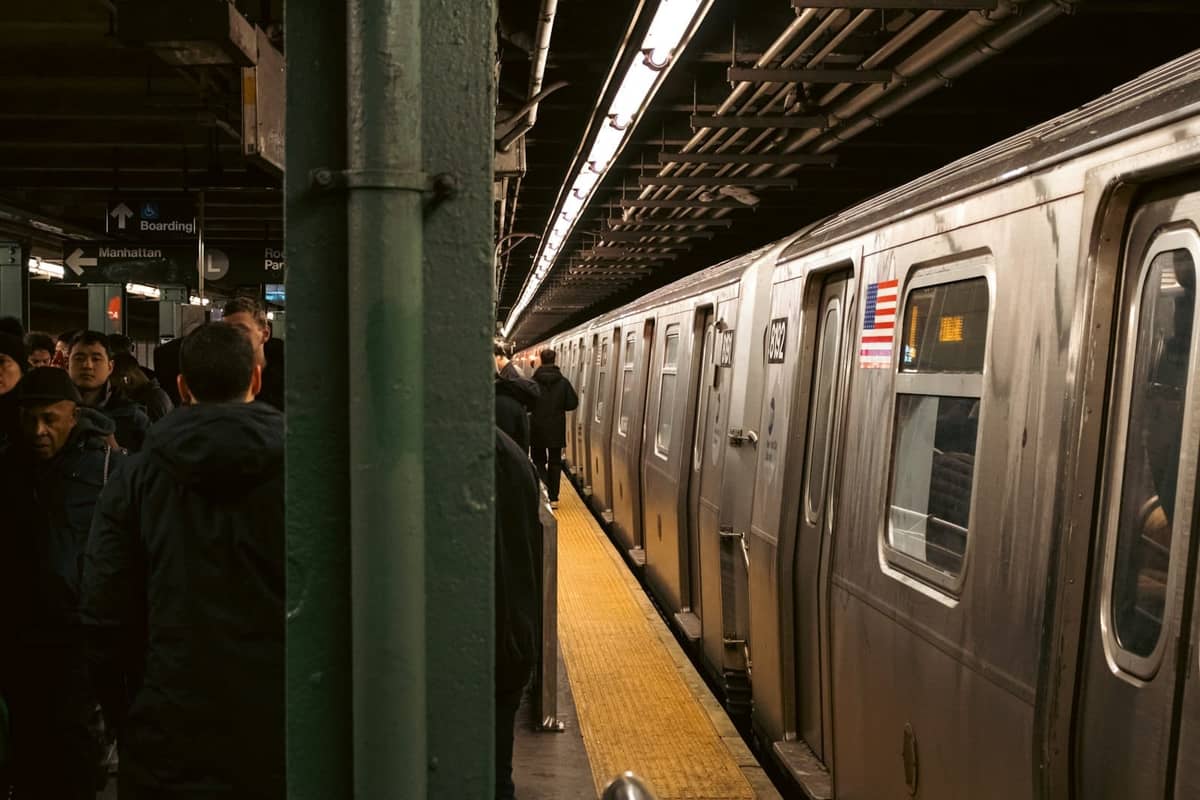 Überfüllter U-Bahnsteig in New York City mit einem einfahrenden Zug und wartenden Fahrgästen.