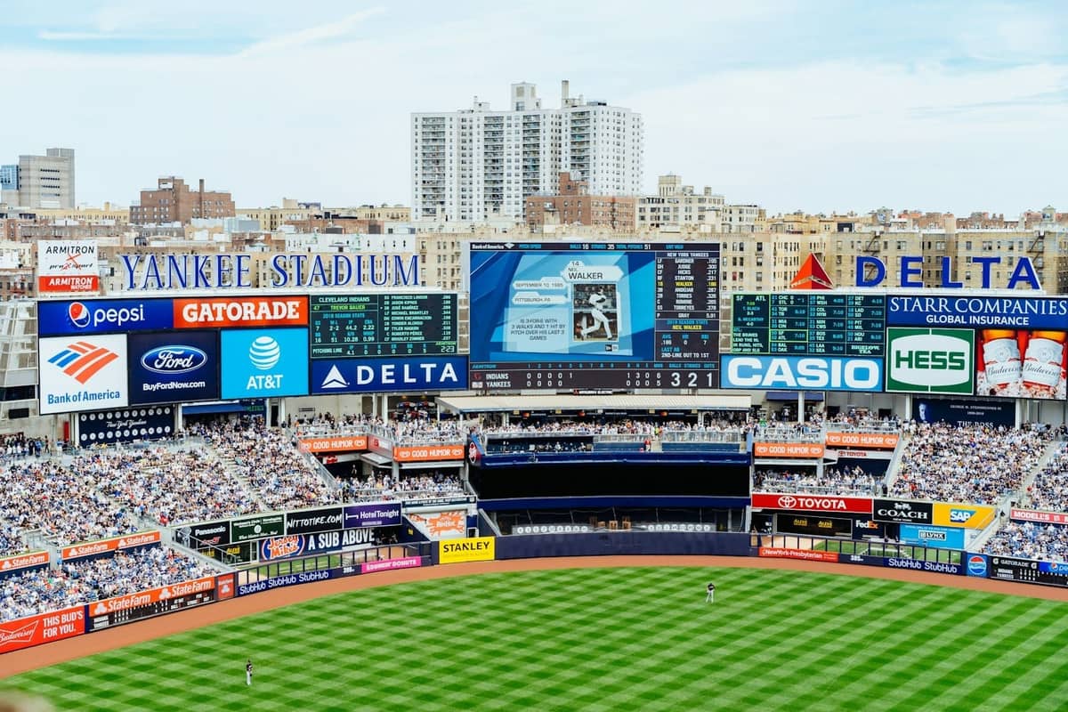 Weitwinkelansicht des Yankee Stadium während eines Baseballspiels mit einer großen Menschenmenge und den Gebäuden von New York im Hintergrund.