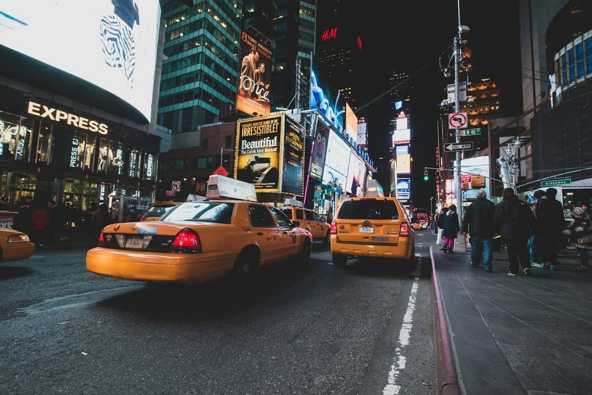 Nächtlicher Blick auf den Times Square mit gelben Taxis, hellen Lichtern und Werbetafeln in Midtown Manhattan, New York City.