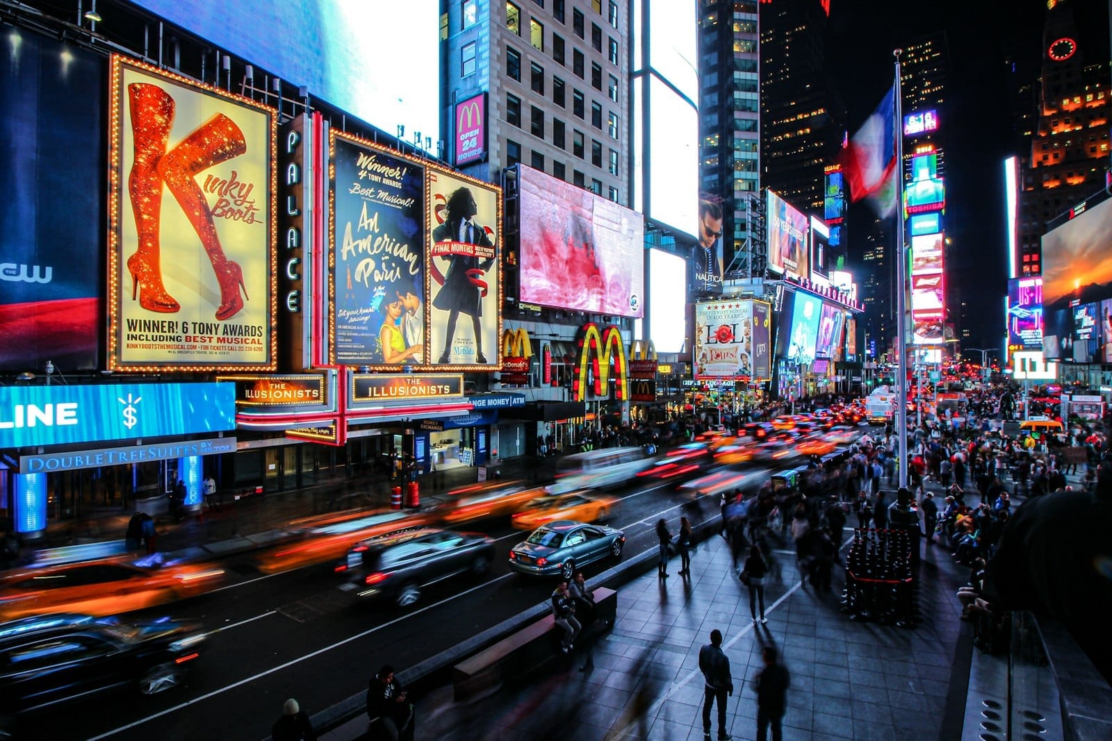 Times Square movimentada à noite, cheia de pessoas, táxis e luzes neon coloridas iluminando a agitada vida noturna de Nova York.