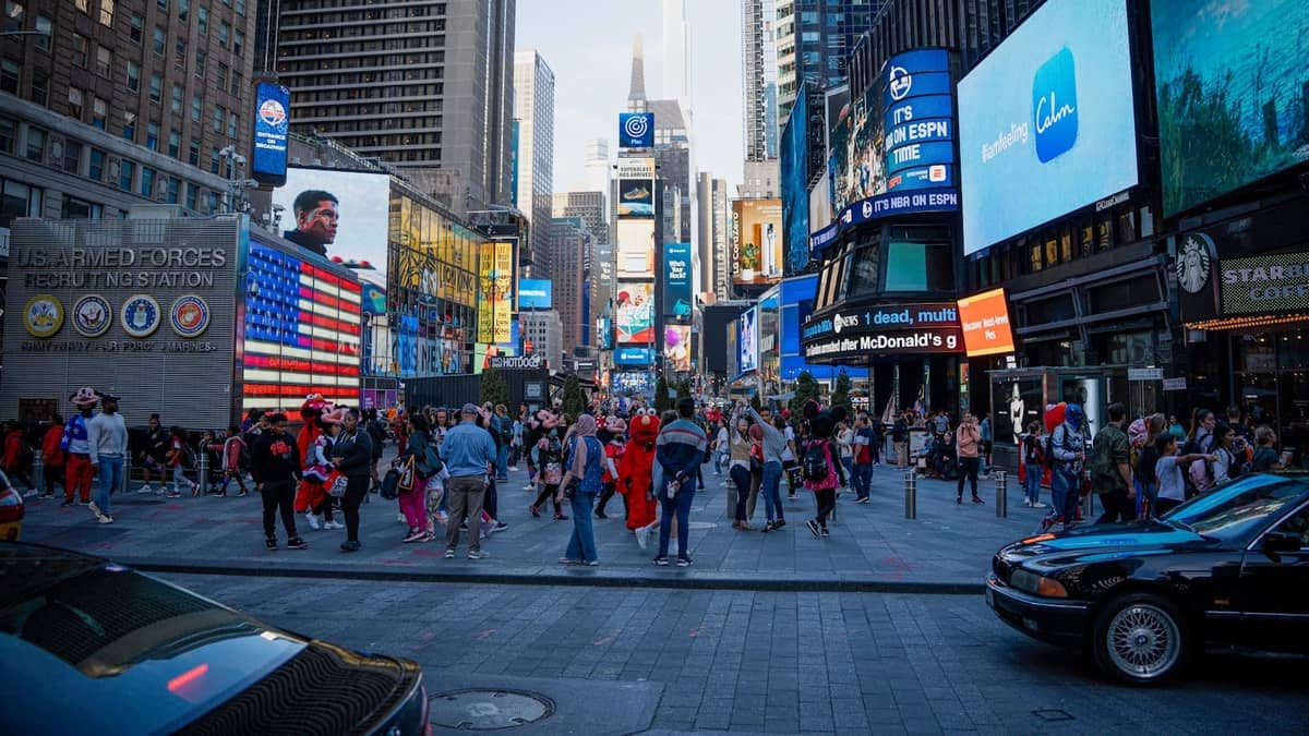 Times Square gefüllt mit Menschenmassen, Kostümkünstlern und bunten Werbetafeln, was auf ein belebtes Gebiet hindeutet, in dem häufige Touristenbetrugsmaschen in NYC vorkommen können.