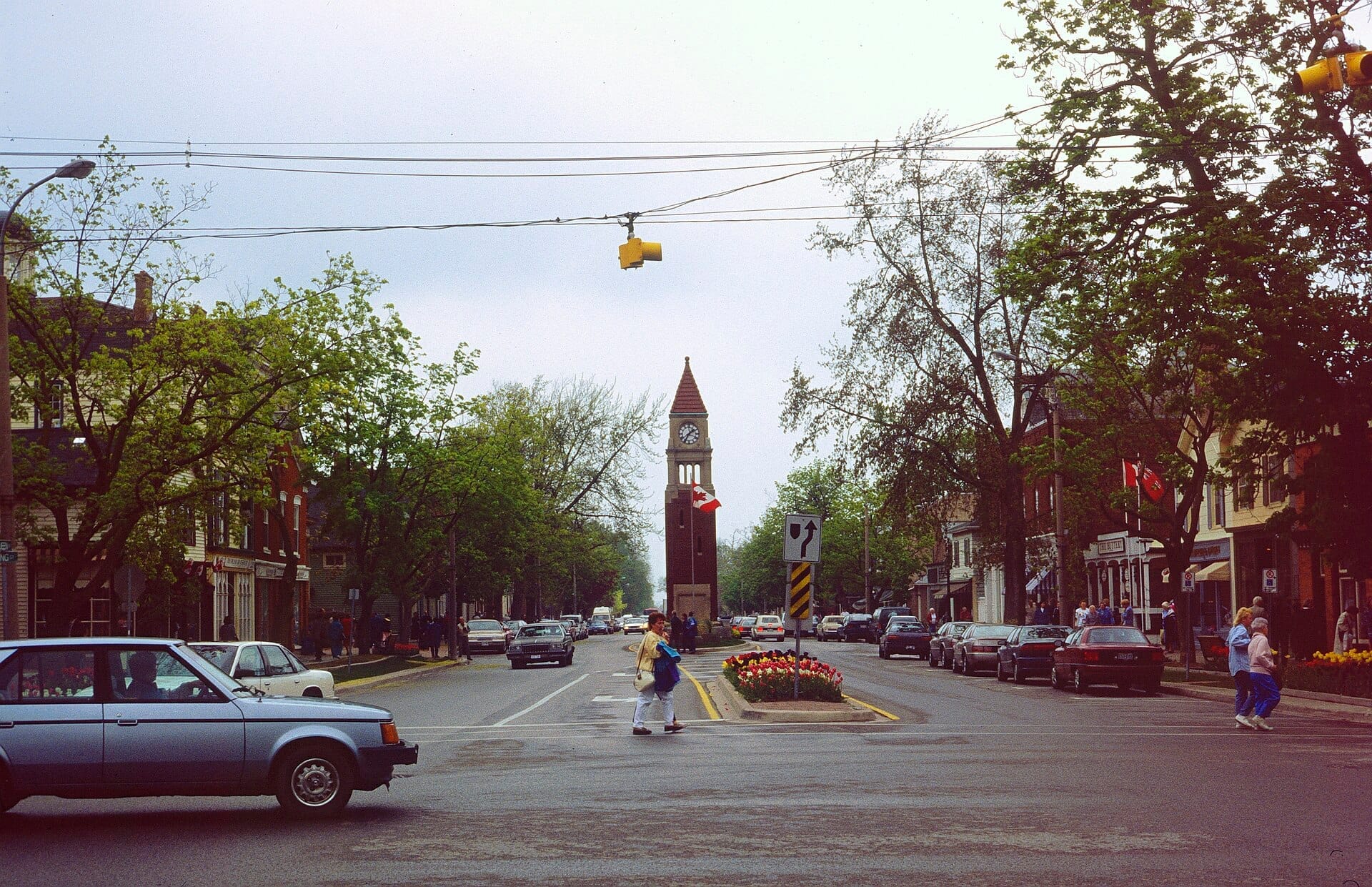 ถนนสายหลักทางประวัติศาสตร์ของ Niagara-on-the-Lake พร้อมหอนาฬิกา รถวินเทจ ร้านค้า และคนเดินถนนในวันที่มีเมฆครึ้มช่วงฤดูใบไม้ผลิ