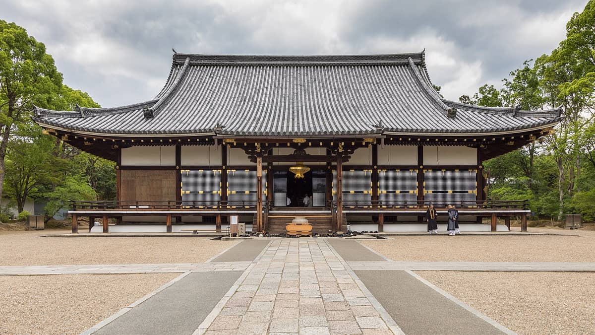 Front view of the main hall of Ninna-ji Temple in Kyoto, showing its traditional wooden architecture and tiled roof surrounded by greenery.