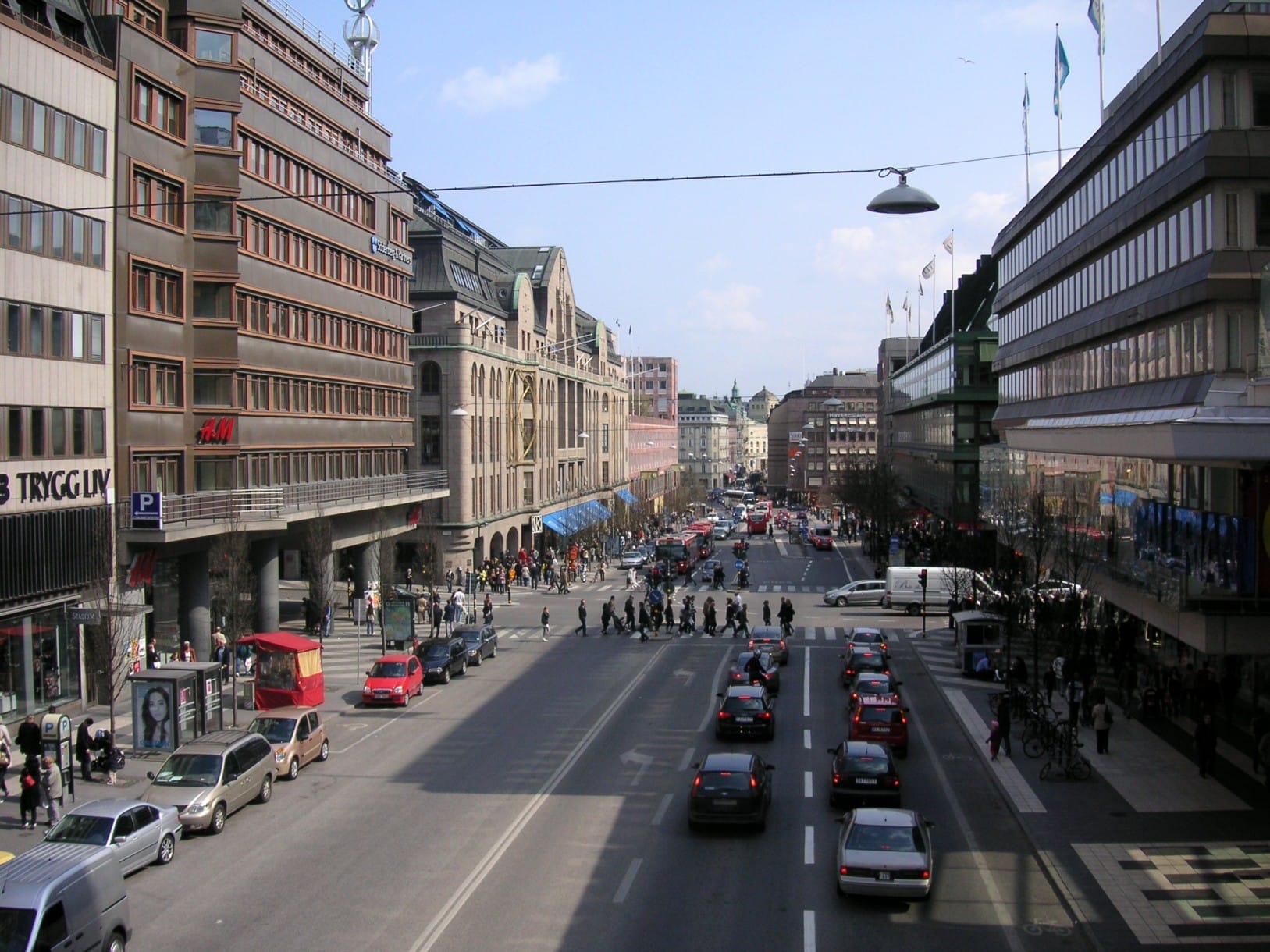 ถนนในเมืองที่คึกคักในย่าน Norrmalm, Stockholm พร้อมอาคารทันสมัย รถยนต์ และผู้คนที่สัญจรไปมาภายใต้ท้องฟ้าแจ่มใสในใจกลางเมือง