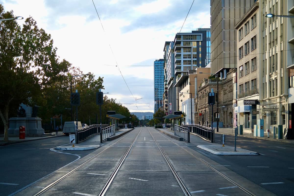 View looking down Adelaide’s North Terrace showing modern buildings, tram tracks, and leafy trees framing the city’s main cultural and university boulevard.