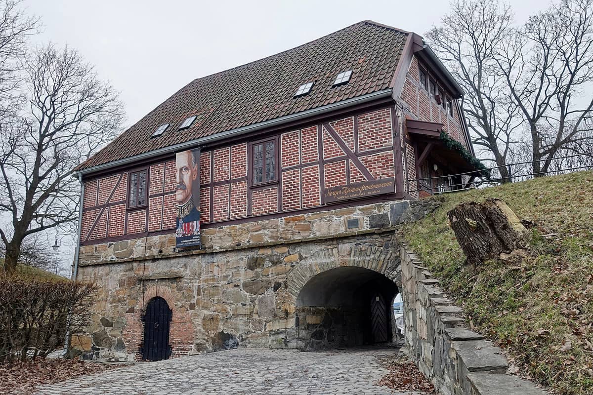 มุมมองภายนอกตัวอาคารพิพิธภัณฑ์ขบวนการต่อต้านนอร์เวย์ (Norges Hjemmefrontmuseum) บนป้อม Akershus อาคารอิฐสีแดงเข้ม ฐานหิน และป้ายผ้าด้านหน้าโดดเด่นสวยงาม