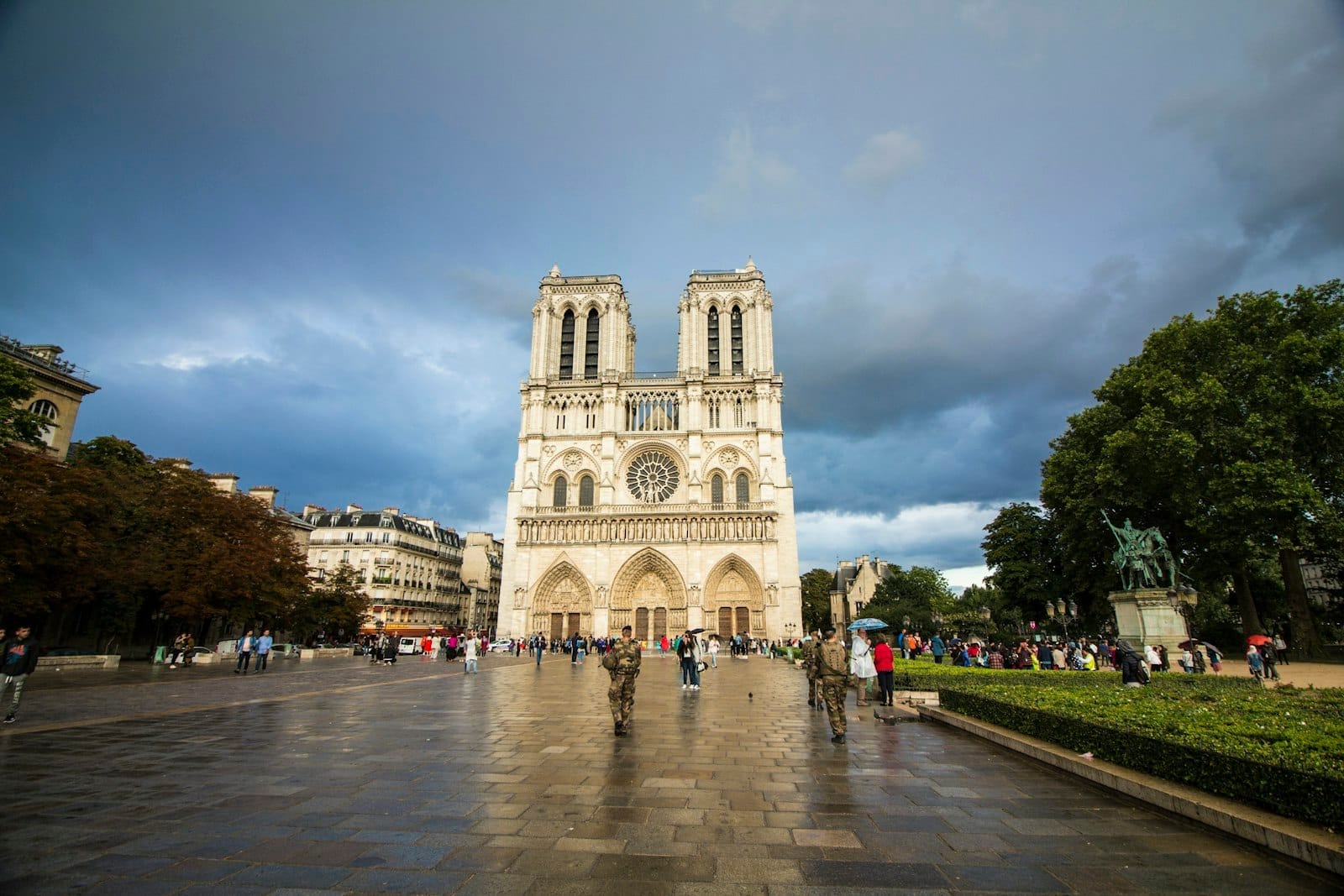 Vista frontale della cattedrale di Notre-Dame con le iconiche due torri, cielo nuvoloso e visitatori riuniti nella piazza antistante, a mostrare la straordinaria architettura gotica.