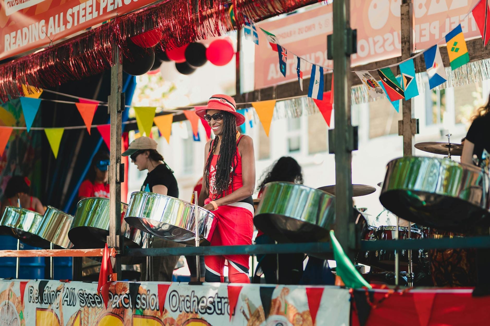 Uma animada banda de steel drum se apresenta em um carro alegórico decorado com bandeiras coloridas no Carnaval de Notting Hill, capturando a atmosfera vibrante do festival.