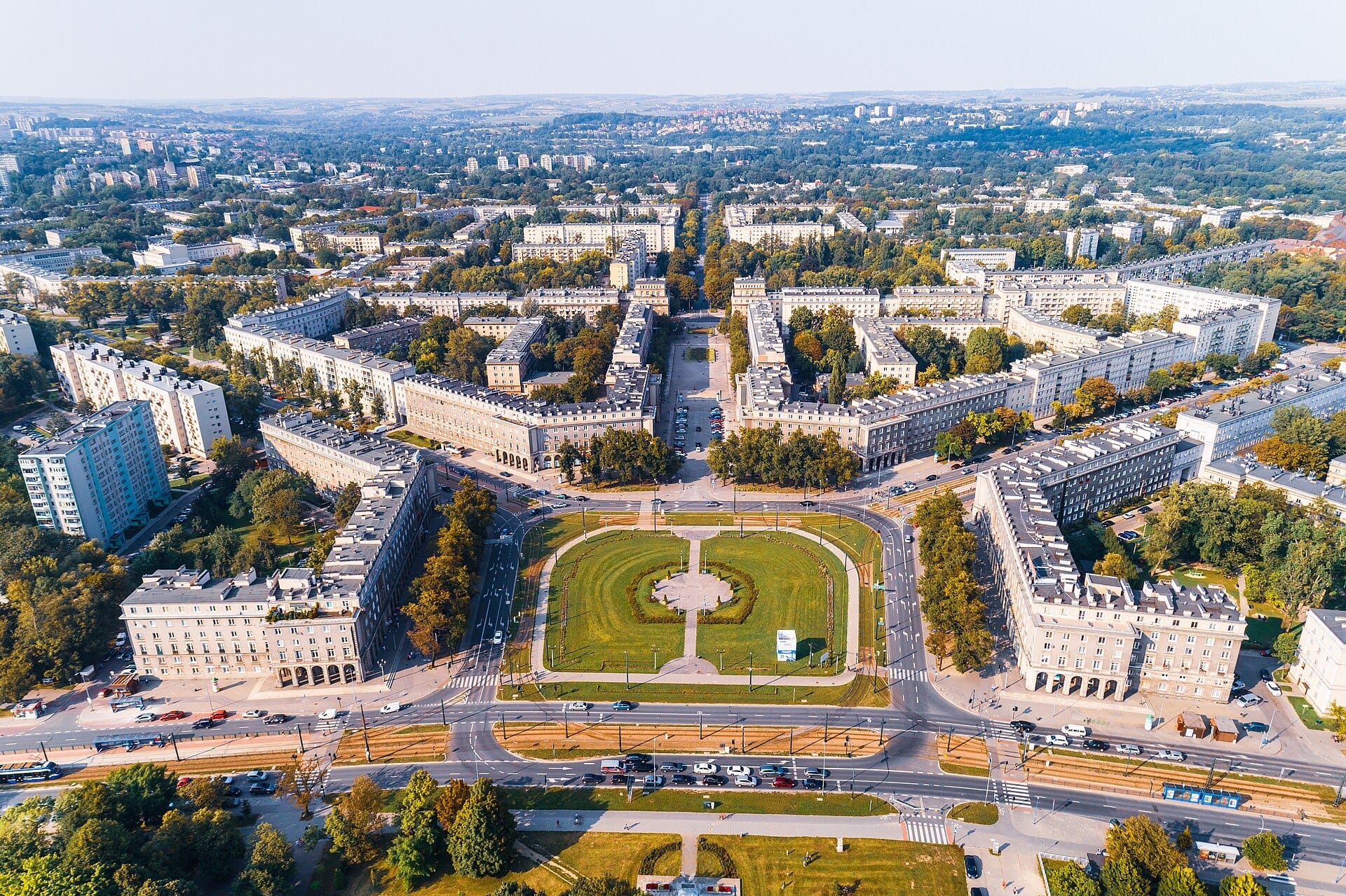 มุมสูงของจัตุรัสกลาง Nowa Huta ใน Kraków เห็นงานสถาปัตยกรรมยุค Stalin แบบสมมาตร พร้อมพื้นที่สีเขียวตรงกลางกว้างใหญ่ ถนนทอดออกเป็นรัศมี ล้อมรอบด้วยเมืองแนวราบ