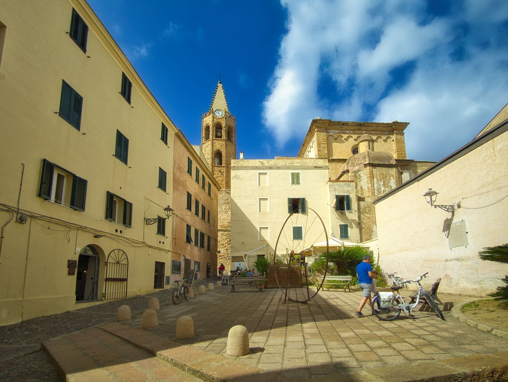 Eine romanische Kirche mit Glockenturm auf einem kleinen Platz, umgeben von historischen Gebäuden in Olbia, Sardinien.