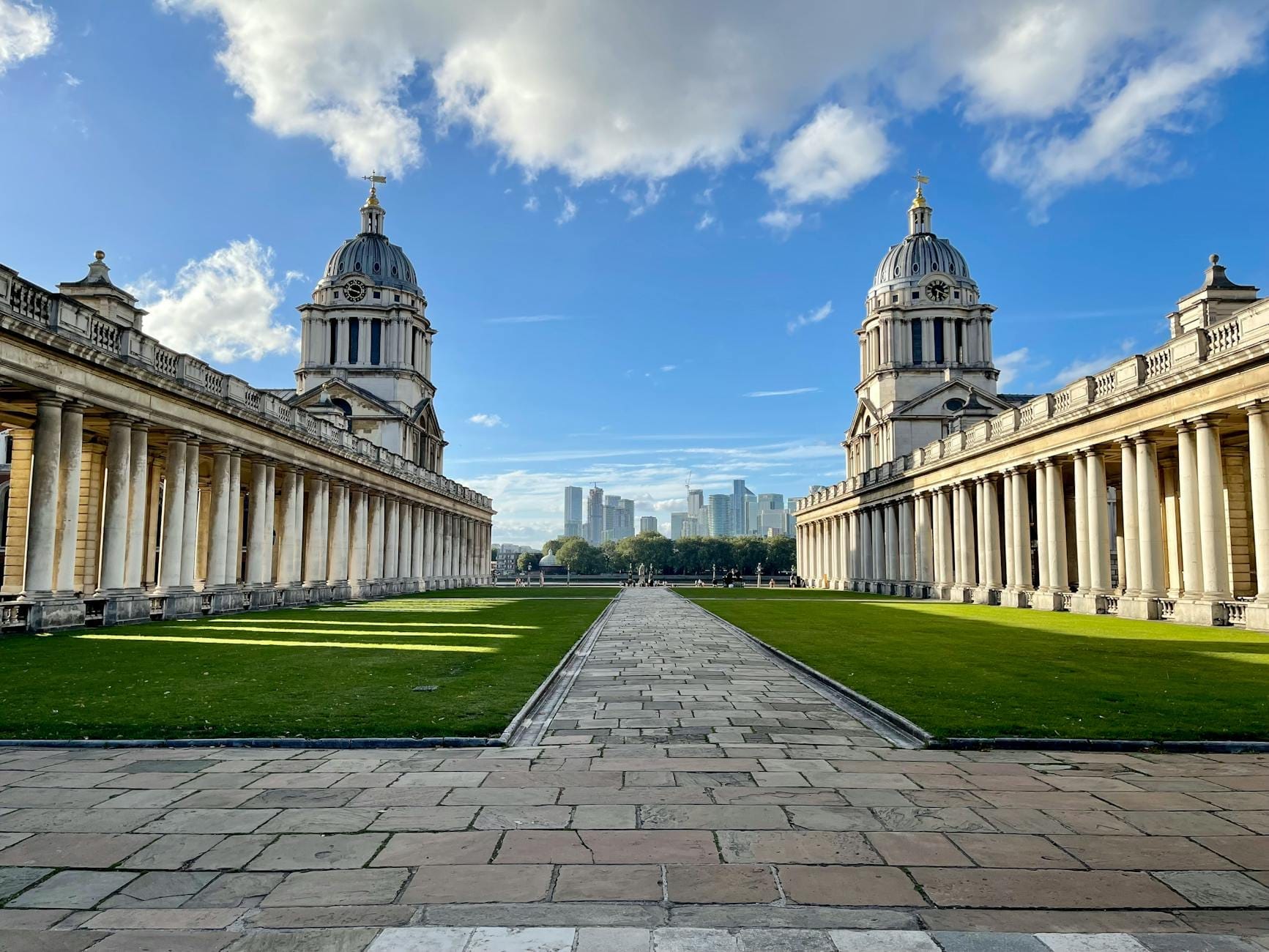 Vista dell'Old Royal Naval College con le iconiche cupole gemelle e i colonnati sotto un cielo azzurro intenso, perfetta come immagine di copertina.