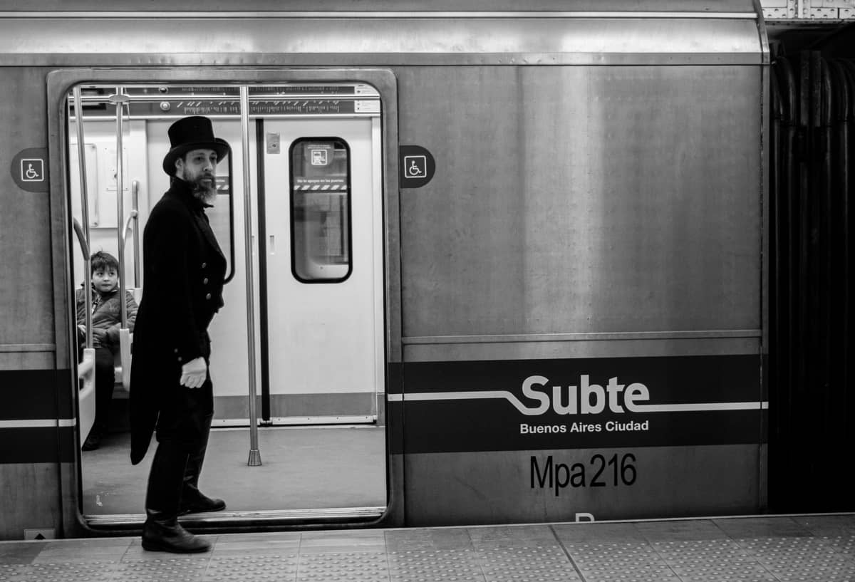 ภาพถ่ายขาวดำของรถไฟ Subte Buenos Aires บนชานชาลาสถานีพร้อมป้าย Subte Buenos Aires ที่มองเห็นได้ชัดเจน