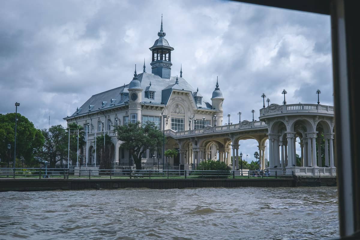 Museo de Arte de Tigre อันเก่าแก่ที่มองเห็นจากแม่น้ำพร้อมต้นไม้เขียวขจีและท้องฟ้ามีเมฆ เป็นทริปวันเดียวยอดนิยมจากบัวโนสไอเรส