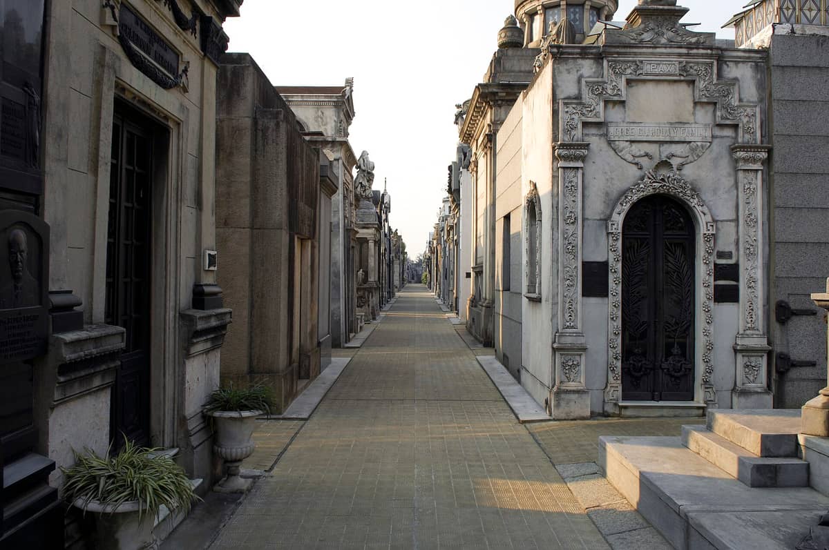 ทางเดินยาวที่เรียงรายด้วยสุสานหินประดับประดาใน Recoleta Cemetery เมือง Buenos Aires ภายใต้แสงกลางวันที่อ่อนนุ่ม