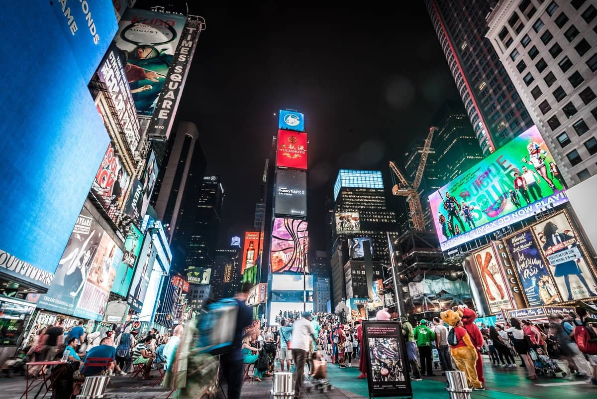 Times Square ในยามค่ำคืนที่เต็มไปด้วยฝูงชน ป้ายโฆษณาสว่างไสว และตึกระฟ้าอันเป็นสัญลักษณ์ของ Midtown Manhattan นครนิวยอร์ก
