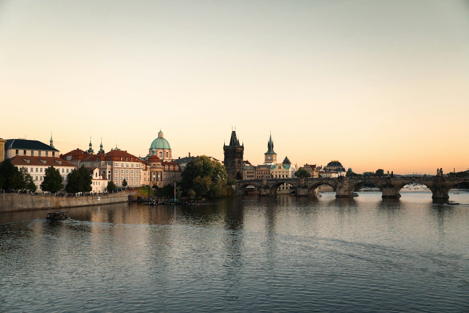 Klassischer Blick auf das Zentrum von Prag mit der Karlsbrücke, der Stadtsilhouette und der Moldau bei Sonnenuntergang.