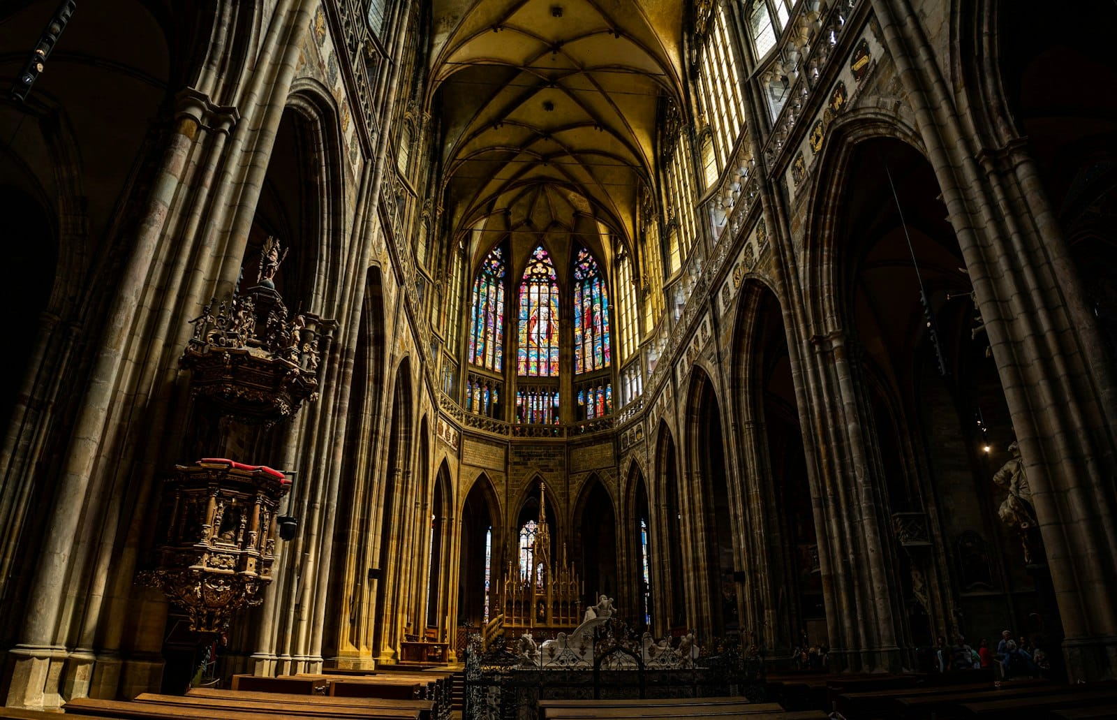 Dramatischer Blick auf das prächtige Innere einer gotischen Kathedrale mit Buntglasfenstern und Gewölbedecken, mit dem Veitsdom auf der Prager Burg.