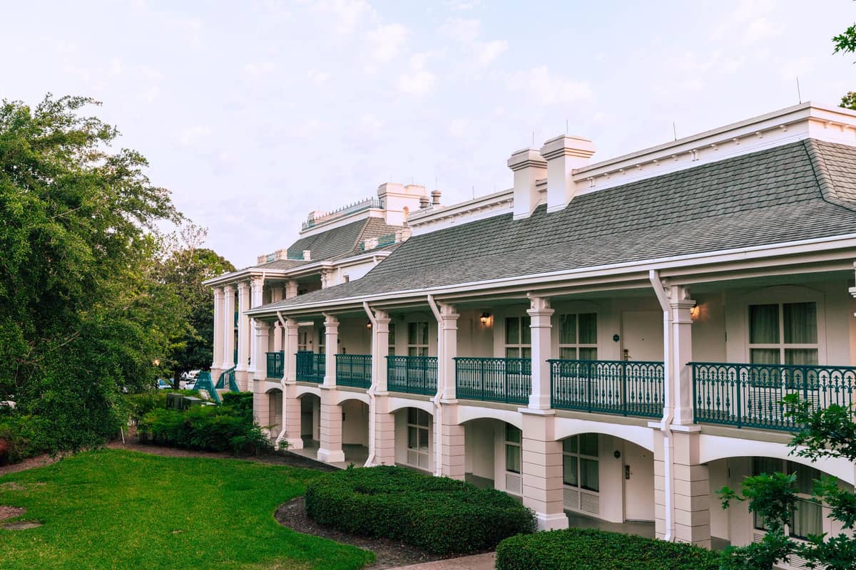 Ein großes, elegantes Hotelgebäude mit von der Südstaaten inspirierten Architektur, weißen Säulen und grünen Geländern, umgeben von gepflegtem Grün in Orlando.