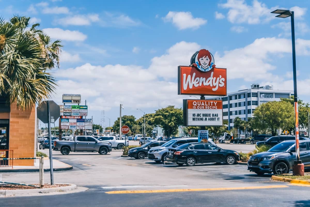Vista esterna di un ristorante fast food Wendy's e altre opzioni di ristorazione informale in una soleggiata via urbana di Orlando