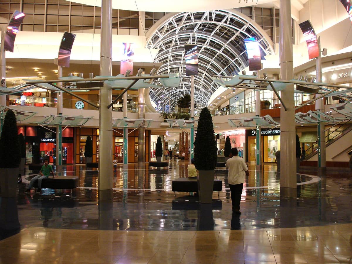Elegantes Inneres der Mall at Millenia in Orlando mit hohen Glasdecken, Designerboutiquen wie Swarovski und polierten Böden mit Einkäufern.