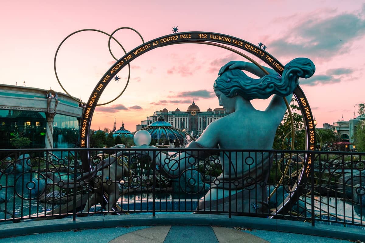 Panoramablick auf Disney Springs bei Sonnenuntergang mit der Art-of-Disney-Fassade, der ikonischen Meerjungfrauenstatue und dem umliegenden Einkaufsviertel – die lebhafte Atmosphäre von Orlandos Themen-Shoppingdestination.