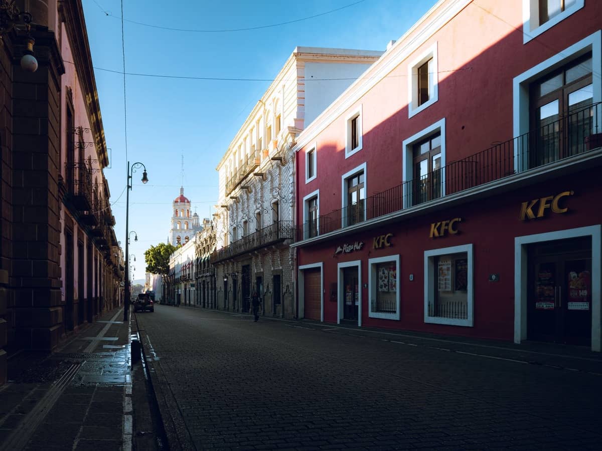 Frühmorgendlicher Blick auf eine ruhige Kopfsteinpflasterstraße, gesäumt von historischen Kolonialgebäuden im Zentrum von Guadalajara.
